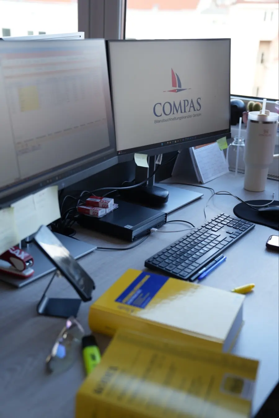 Arbeitsplatz der Lohnverrechnung mit Doppelmonitor und Fachliteratur